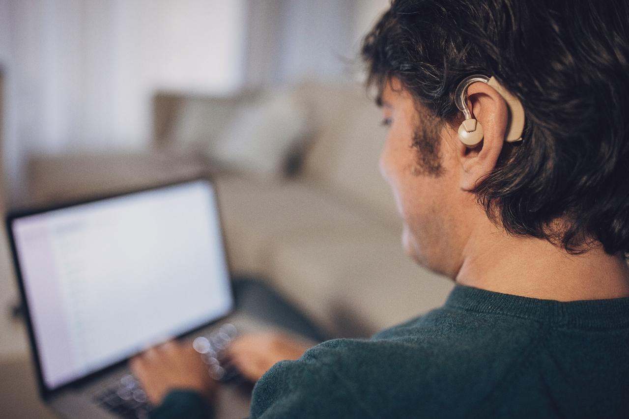 Man using laptop with a hearing aid