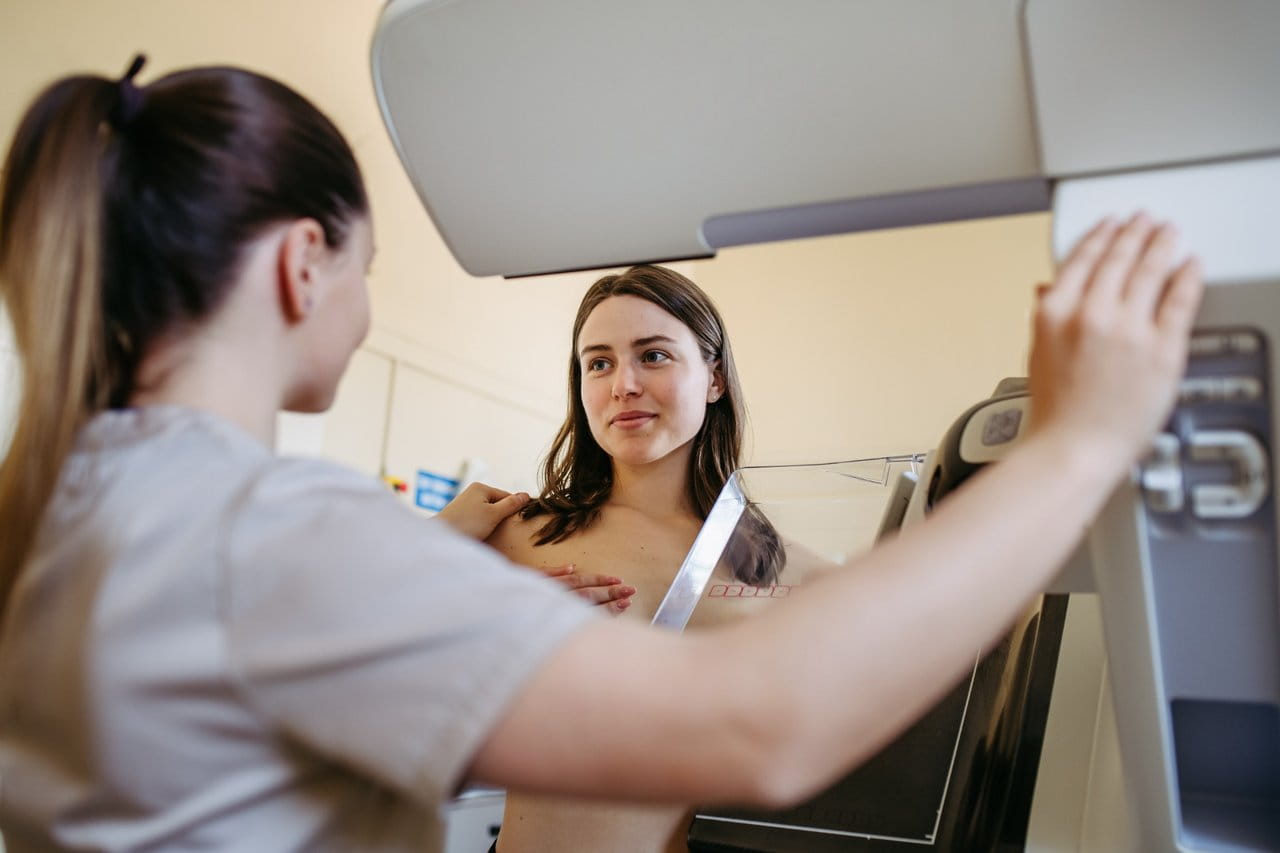 Technologist positions woman for mammogram exam.