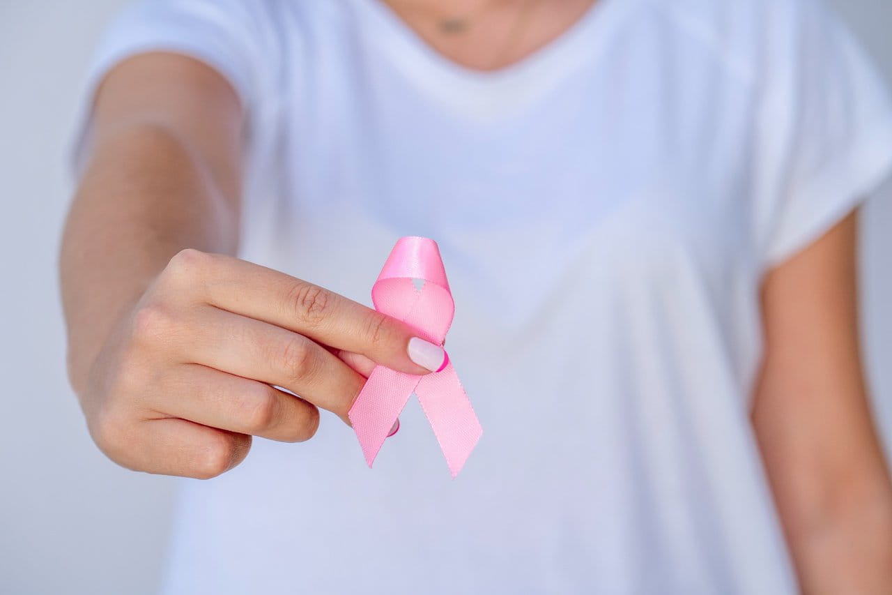 Hand holding pink breast-cancer ribbon.