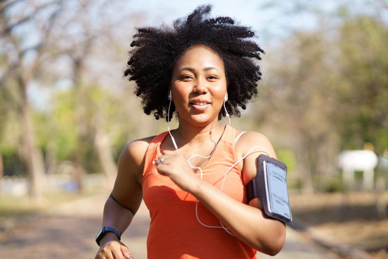 Smiling woman jogging with earphones in a park