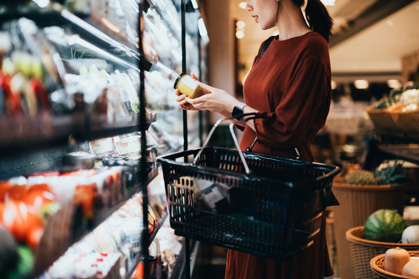 Person reading a food label in a grocery store aisle.