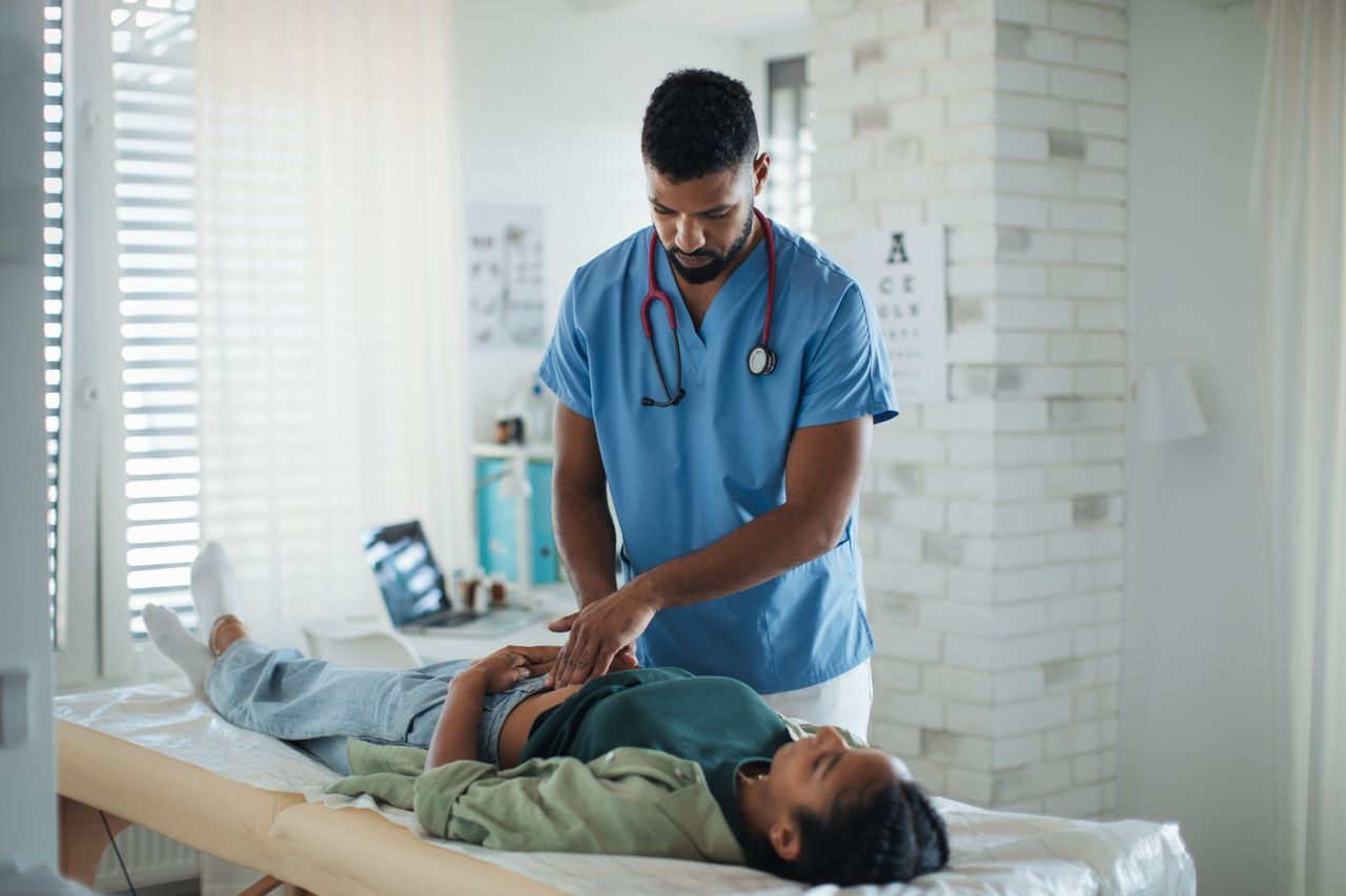 Doctor examining woman’s abdomen.