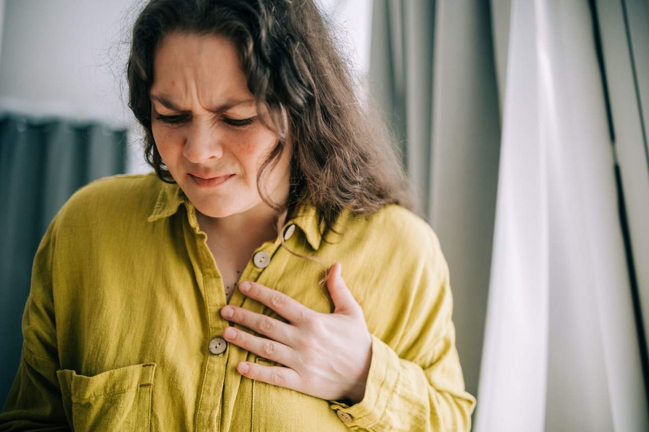 Woman clutching chest in pain, showing possible heartburn or chest discomfort