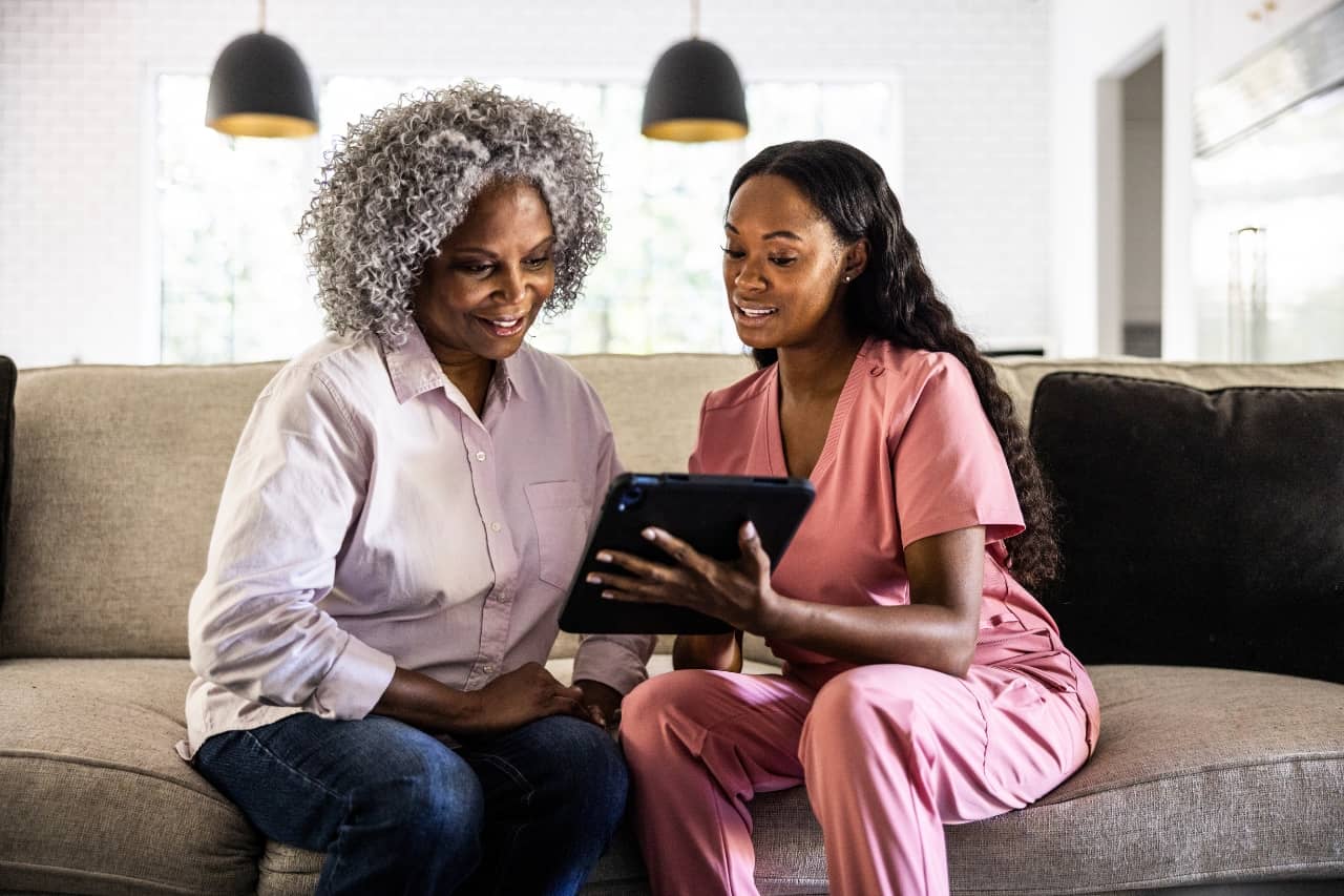 Home Health Care Nurse and Patient Looking at Technology
