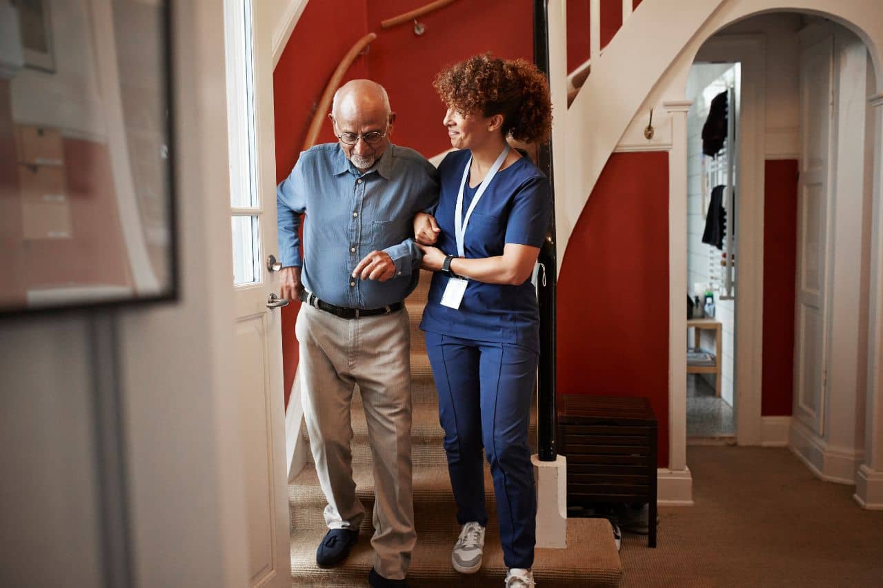Home Health Nurse helping a man walk