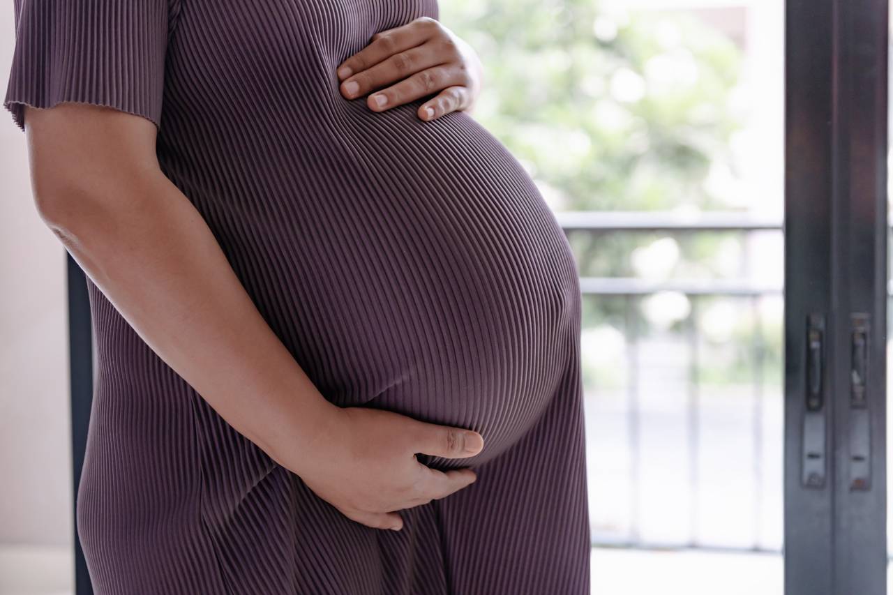 Pregnant woman cradling belly.