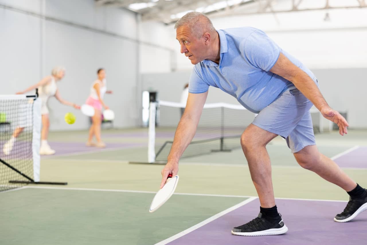 older man playing pickleball