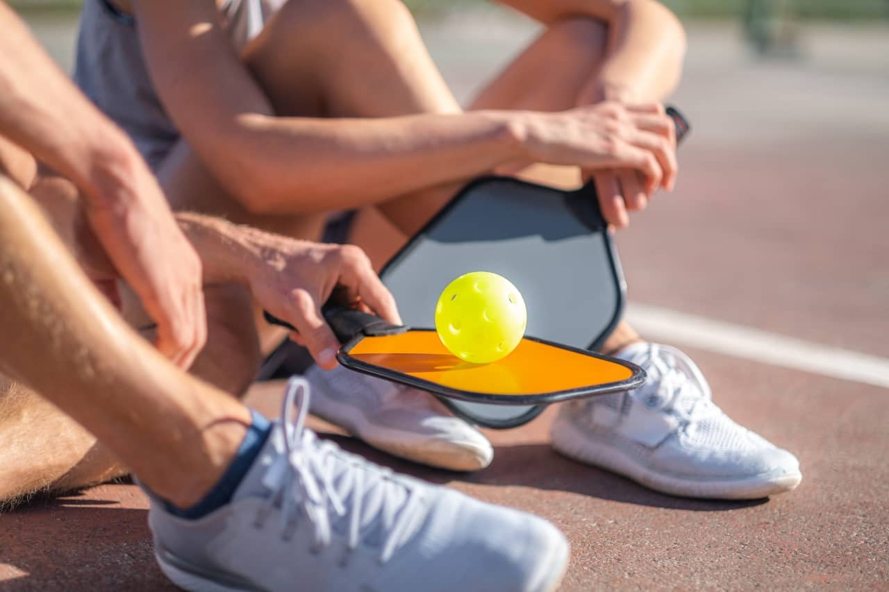 Two people sitting down on a pickleball court hydration