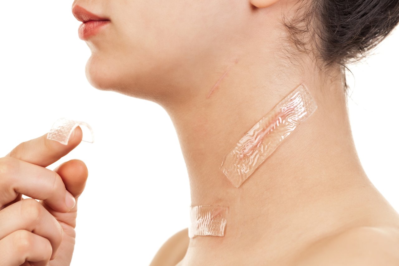 Close-up of a woman applying silicone scar tape on her neck