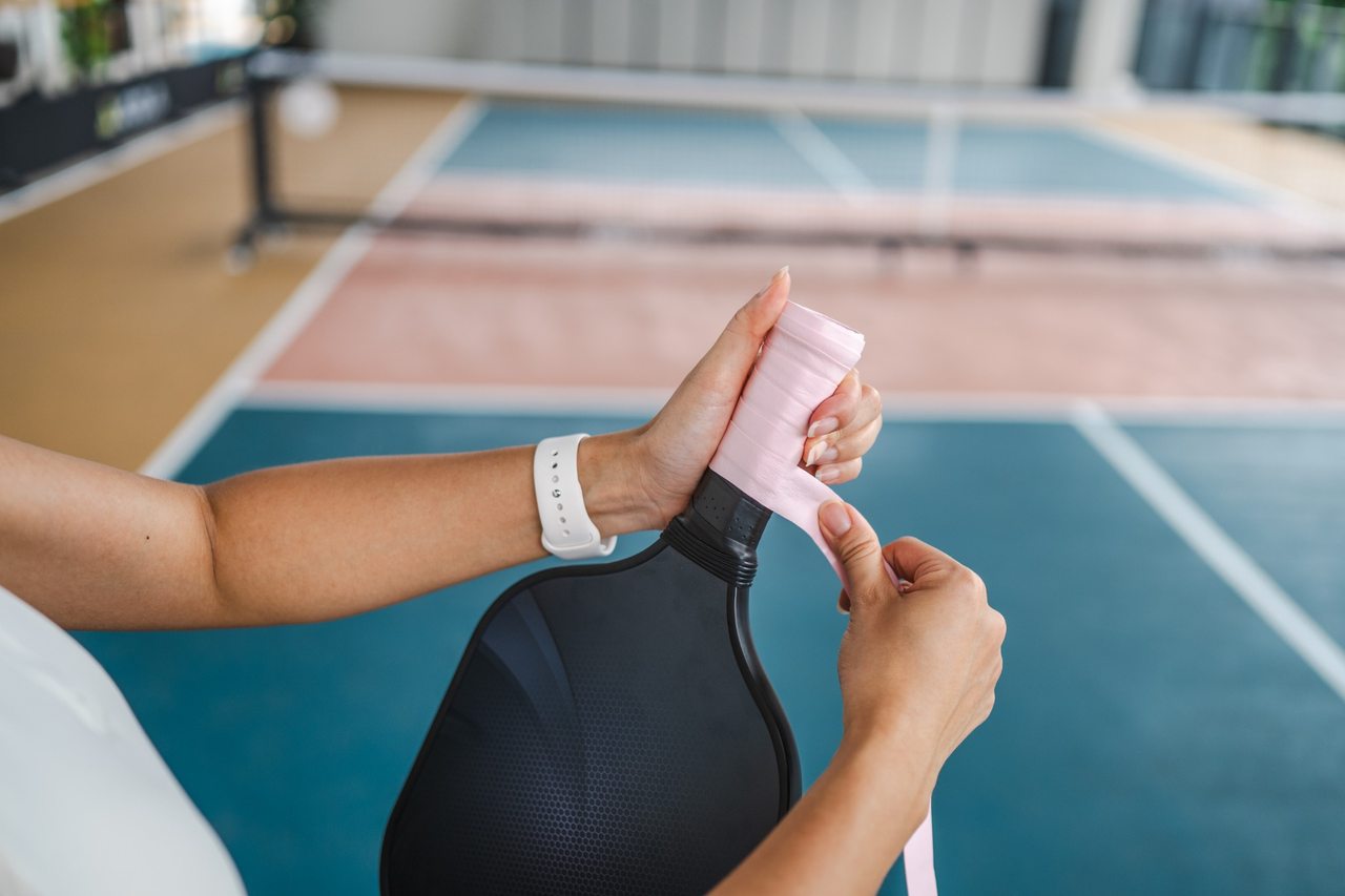 Woman wrapping the handle of a pickleball paddle