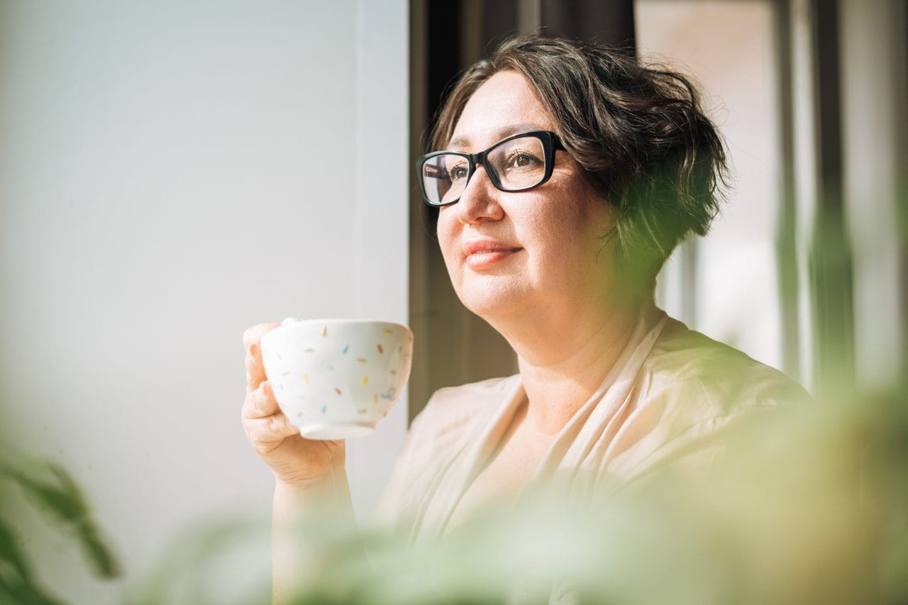 Woman drinking coffee by a window
