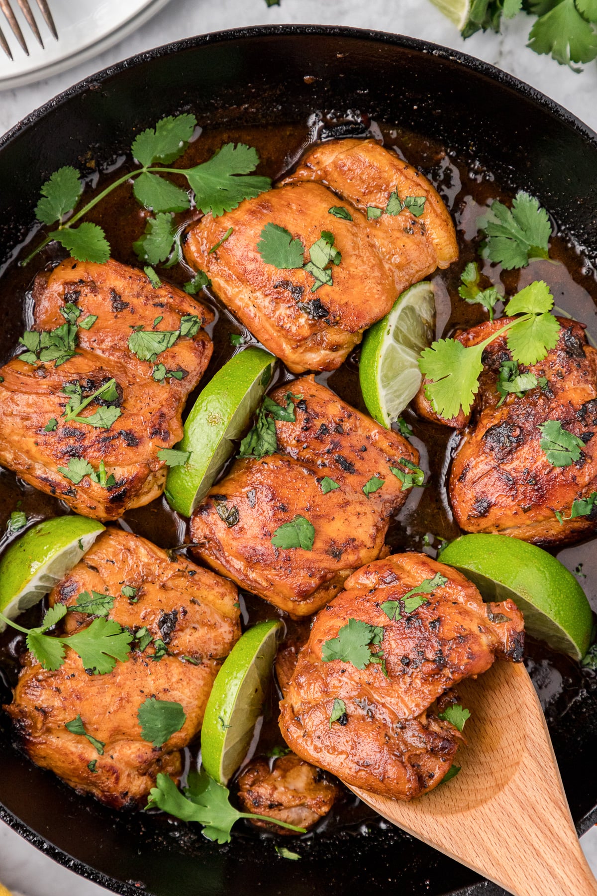 Cilantro lime chicken being scooped out of iron skillet.