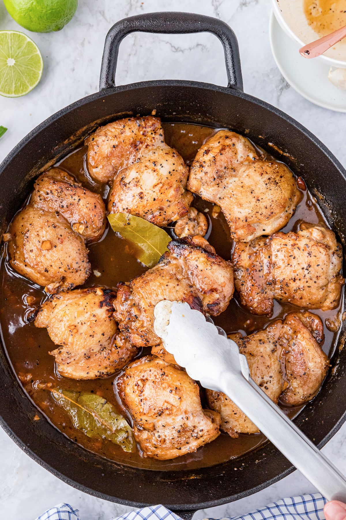 Cooking chicken adobo in a cast iron skillet.