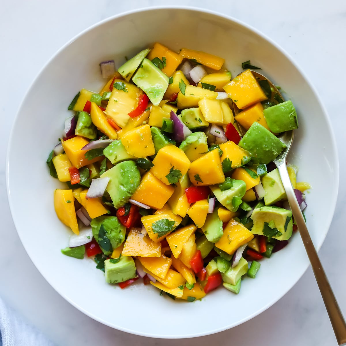 Mango avocado salad in a white bowl.