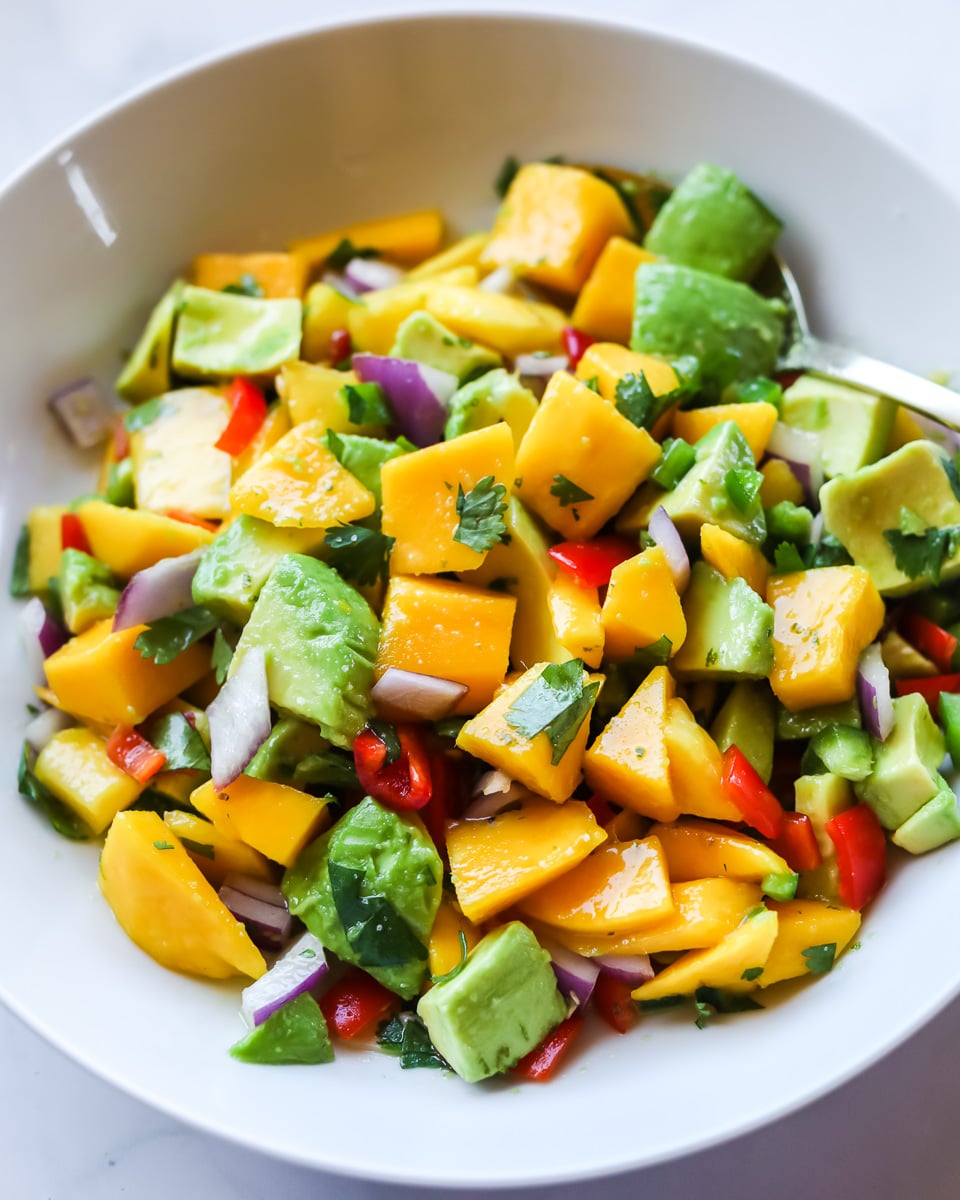 Mango avocado salad in a white bowl.
