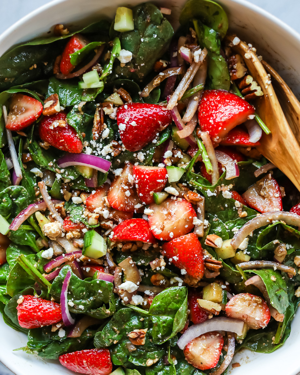 Closeup of strawberry spinach salad in white bowl.