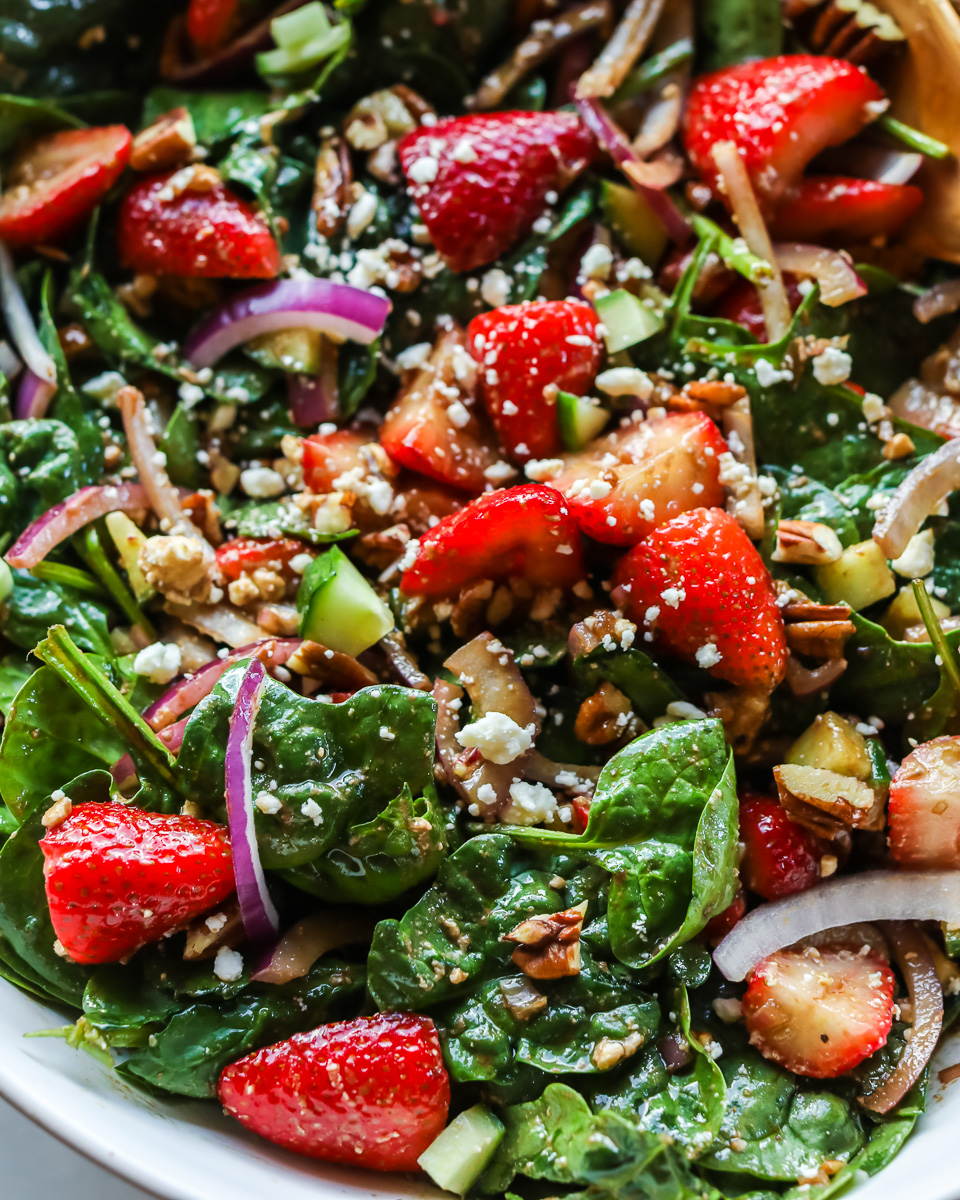 Closeup of strawberry spinach salad in white bowl.