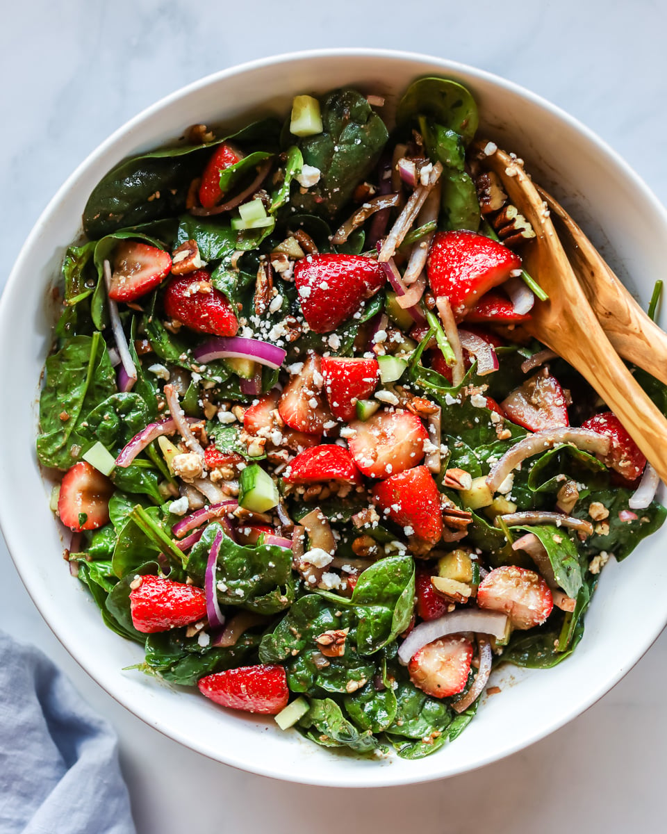 Strawberry spinach salad in white bowl.