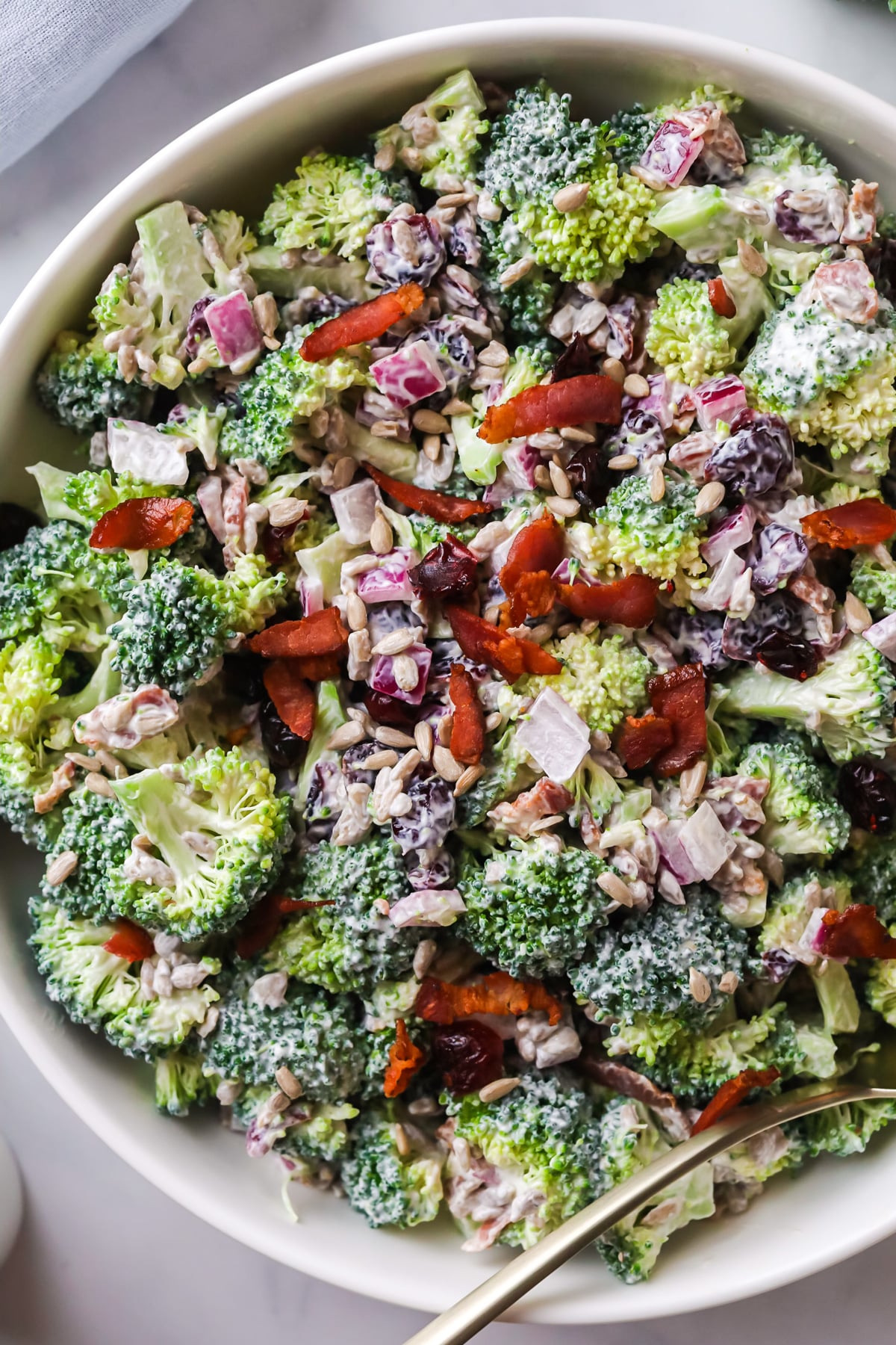 Broccoli salad in a white bowl with bacon.